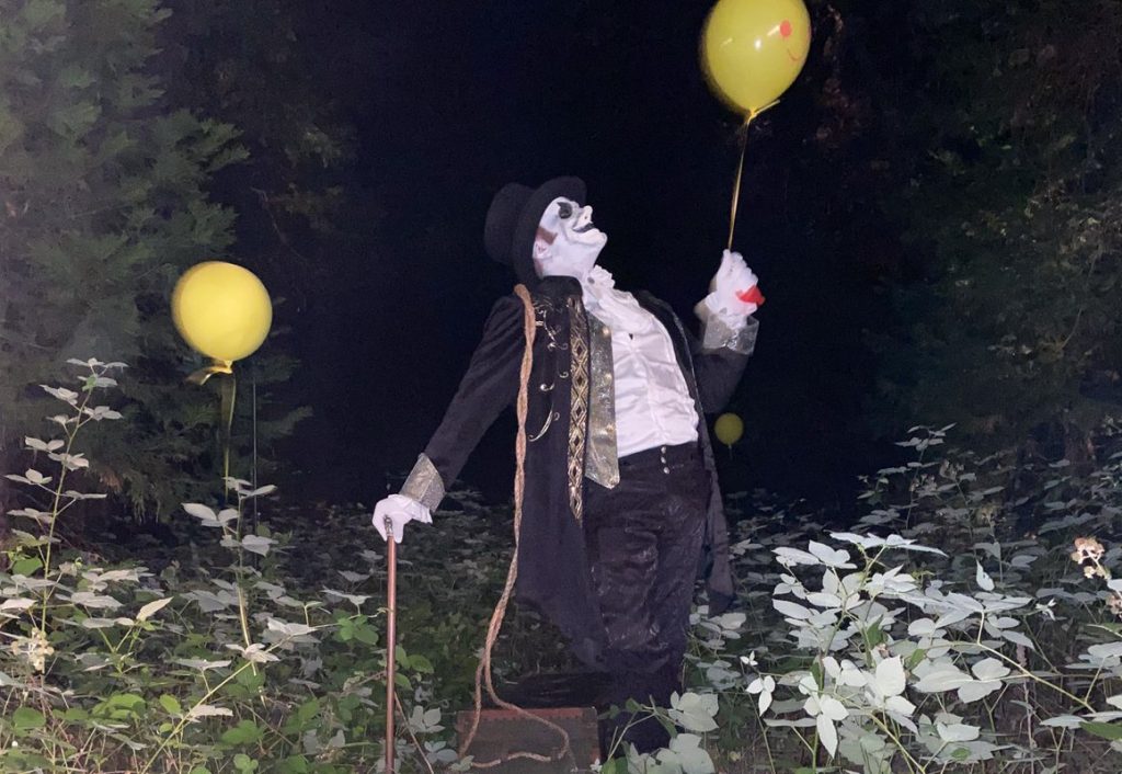 Ringmaster Vincent Vile holding a yellow balloon in the woods at night